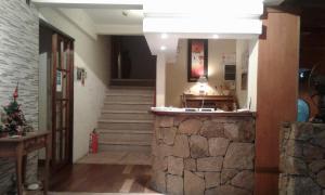 a lobby with a staircase and a stone wall at Principado Sierras Hotel in Mina Clavero