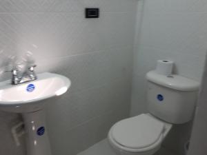 a white bathroom with a toilet and a sink at Hotel Media Luna in Santa Marta