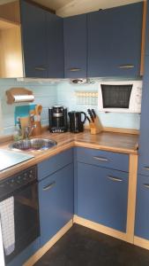 a blue kitchen with a sink and a microwave at Ferienhaus " Silly " am schönen Listersee in Meinerzhagen