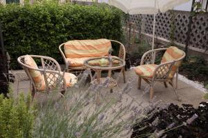 three chairs and a table in a garden with an umbrella at Apartments Mali Raj in Vranjic