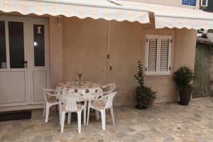 - une table et des chaises sur la terrasse d'une maison dans l'établissement Apartments Mali Raj, à Vranjic