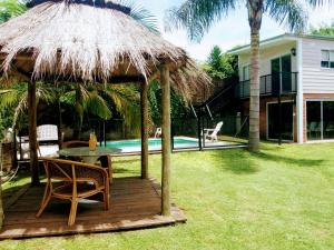 a wooden deck with a table and a straw umbrella at CASA DE RELAX CON PISCINA in Paraná