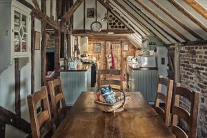a kitchen with a wooden table and chairs at Coldharbour Cottage with Hot Tub in Stone