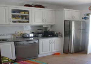 eine Küche mit weißen Schränken und einem Kühlschrank aus Edelstahl in der Unterkunft Vivenda V3 Praia Verde in Castro Marim