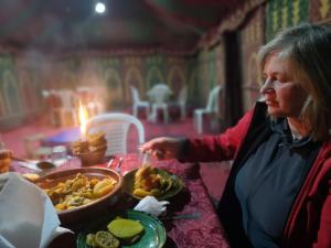 kobieta siedząca przy stole z talerzem jedzenia w obiekcie Erg Chigaga Camp Shooting Stars w mieście Mhamid (Amhamid al-Ghizlan)