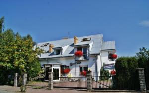 ein weißes Haus mit roten Blumen an den Fenstern in der Unterkunft Domki "Berenika" in Rewal