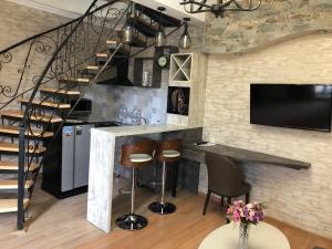 a kitchen with a bar with stools and a tv at ApartHotel Heart of Tbilisi in Tbilisi City