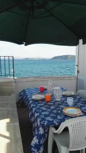 a table with a blue and white table cloth and the ocean at Terrazzo 73 in Ischia