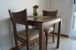una mesa de madera con 2 sillas y un jarrón. en Zen Boutique Apart Hotel, en La Paloma