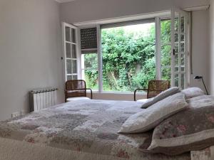 ein Schlafzimmer mit einem Bett und einem großen Fenster in der Unterkunft El Jacarandá, relax, en Chascomús in Chascomús