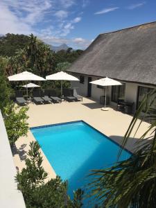 a swimming pool in front of a house with umbrellas at Cape Vermeer in Somerset West