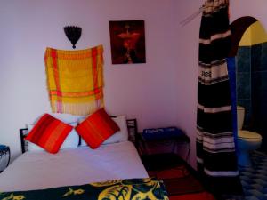 a bedroom with a bed with red and yellow pillows at Kasbah Les Nomades in Skoura