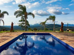 a swimming pool with palm trees and mountains in the background at Hotel Vila Relicário in Ouro Preto