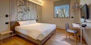 a bedroom with a bed and a desk and a television at Park Hotel & Residence by The Cube in Fidenza