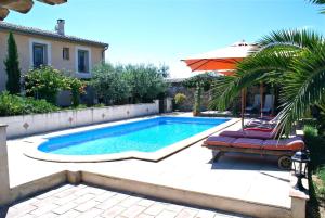 a swimming pool with two lounge chairs and an umbrella at Mas Tolosan in Vauvert