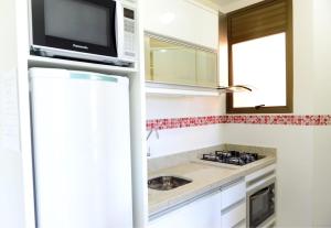 a kitchen with a microwave and a sink at Apartamento frente à praia! in Florianópolis