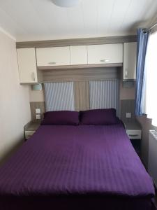 a bedroom with a purple bed in a room at 3 bedroom caravan with hot tub Tattershall lakes in Tattershall