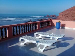 two white lounge chairs on a balcony overlooking the ocean at HOTEL BEACH CLUB LEGZIRA in Sidi Ifni
