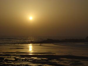 a sunrise on the beach with the sun in the sky at HOTEL BEACH CLUB LEGZIRA in Sidi Ifni