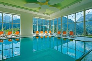 a swimming pool with orange chairs and windows at Hotel Alte Krone in Mittelberg