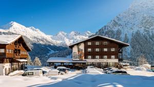 a ski lodge with cars parked in the snow at Hotel Alte Krone in Mittelberg