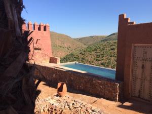 a swimming pool in a building with mountains in the background at Hotel De Charme Les 3 Chameaux 4 étoiles in Mirleft