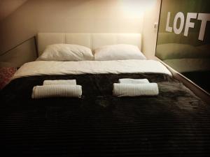 a bed with two pillows and two towels on it at Loft Osijek in Osijek