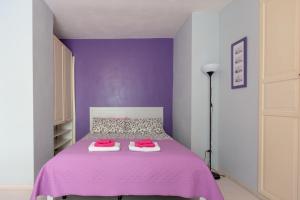 um quarto roxo com uma cama com lençóis cor-de-rosa em FV STUDIOS Chiaia em Nápoles