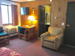 Habitación de hotel con cama, silla y escritorio. en Granada Inn Motel - Kalkaska, en Kalkaska
