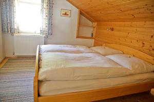 een groot bed in een houten kamer met een raam bij Klausmoarhof in Leisach