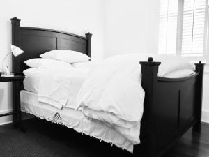 a black and white bed with white sheets and pillows at Petite Desire in New Orleans