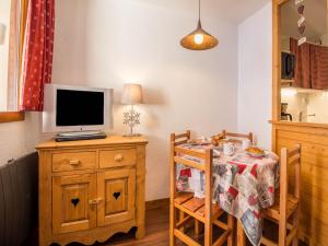 a kitchen with a table with a television and a table with chairs at 26 Praz de l'Ours Vallandry - Paradiski in Peisey-Nancroix