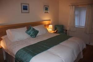 a bedroom with a large bed with two green pillows at The Anvil Lodge in Shifnal