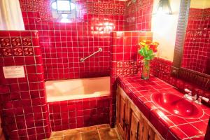 Baño de azulejos rojos con lavabo y espejo en Hotel Casa Encantada en Pátzcuaro