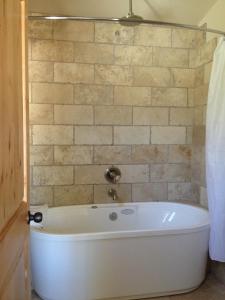 a white tub in a bathroom with a brick wall at Stone Canyon Inn in Tropic