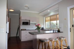 a kitchen with white cabinets and a counter with stools at Rural Ambience with Netflix in Mount George