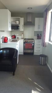 a kitchen with white cabinets and a stove top oven at Rosedale Cottages in Twizel