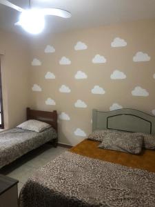 1 dormitorio con 2 camas y nubes en la pared en Residencial Christal Das Flores, en Florianópolis