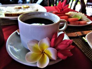 a cup of coffee and a flower on a table at La Bila Dive Resort Amed in Amed