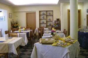 un restaurant avec tables et chaises et nappes blanches dans l'établissement Hotel Lido, à Lido di Jesolo