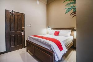 a bedroom with a large bed with a red pillow at RedDoorz Plus near Mall Slipi Jaya in Jakarta