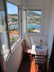 una mesa pequeña y sillas en una habitación con ventanas grandes en Sinistaj Rooms, en Dubrovnik