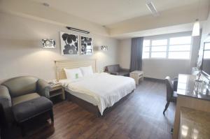 Habitación de hotel con cama, escritorio y sillas en Kindness Hotel-Qixian en Kaohsiung