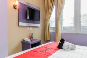 a bedroom with a bed with a tv on the wall at RedDoorz Plus near Stasiun Bekasi in Bekasi