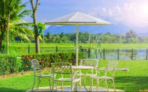 a table and chairs with an umbrella in a field at Lavendish Wild Safari in Wasgamuwa