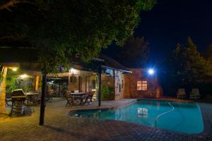Bayswater Lodge في بلومفونتين: مسبح في الليل مع طاولة وكراسي