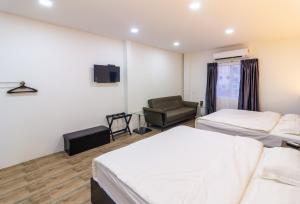 a hotel room with two beds and a chair at Tambun Warm Hotel in Ipoh