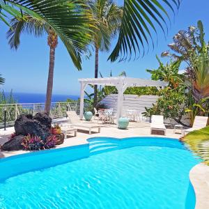 uma piscina com um gazebo e o oceano em LA BOHEME, résidence de 5 appartements avec piscine, vue océan, Petite Ile em Petite Île