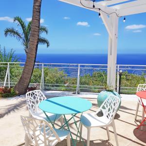 uma mesa e cadeiras com o oceano ao fundo em LA BOHEME, résidence de 5 appartements avec piscine, vue océan, Petite Ile em Petite Île