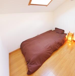 a bed in a white room with a lamp on the floor at Niseko Guesthouse Nalu. in Niseko